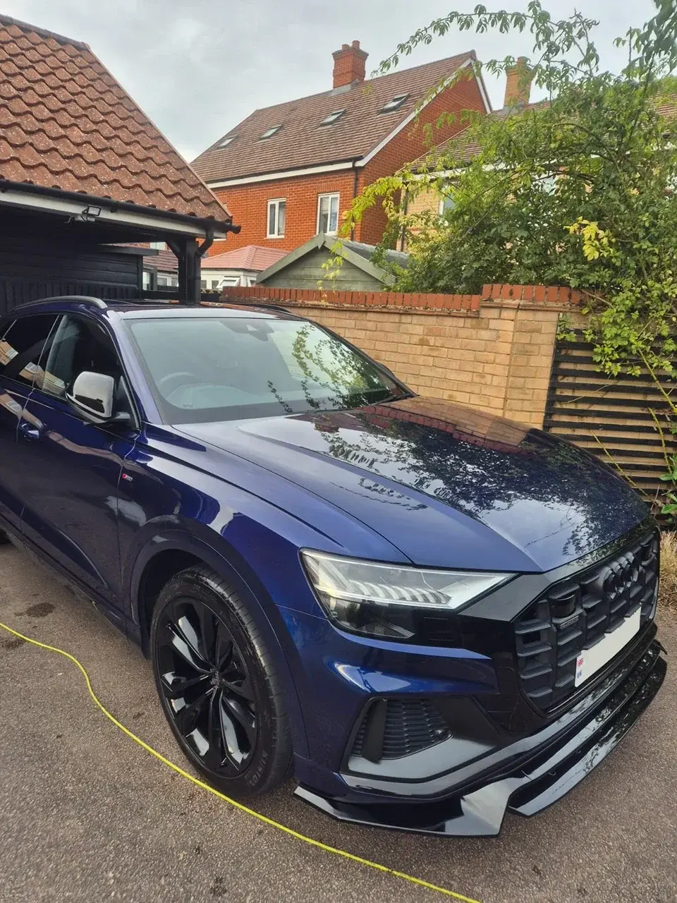 Dark blue Audi on a driveway with a yellow power cable running across the ground beside it