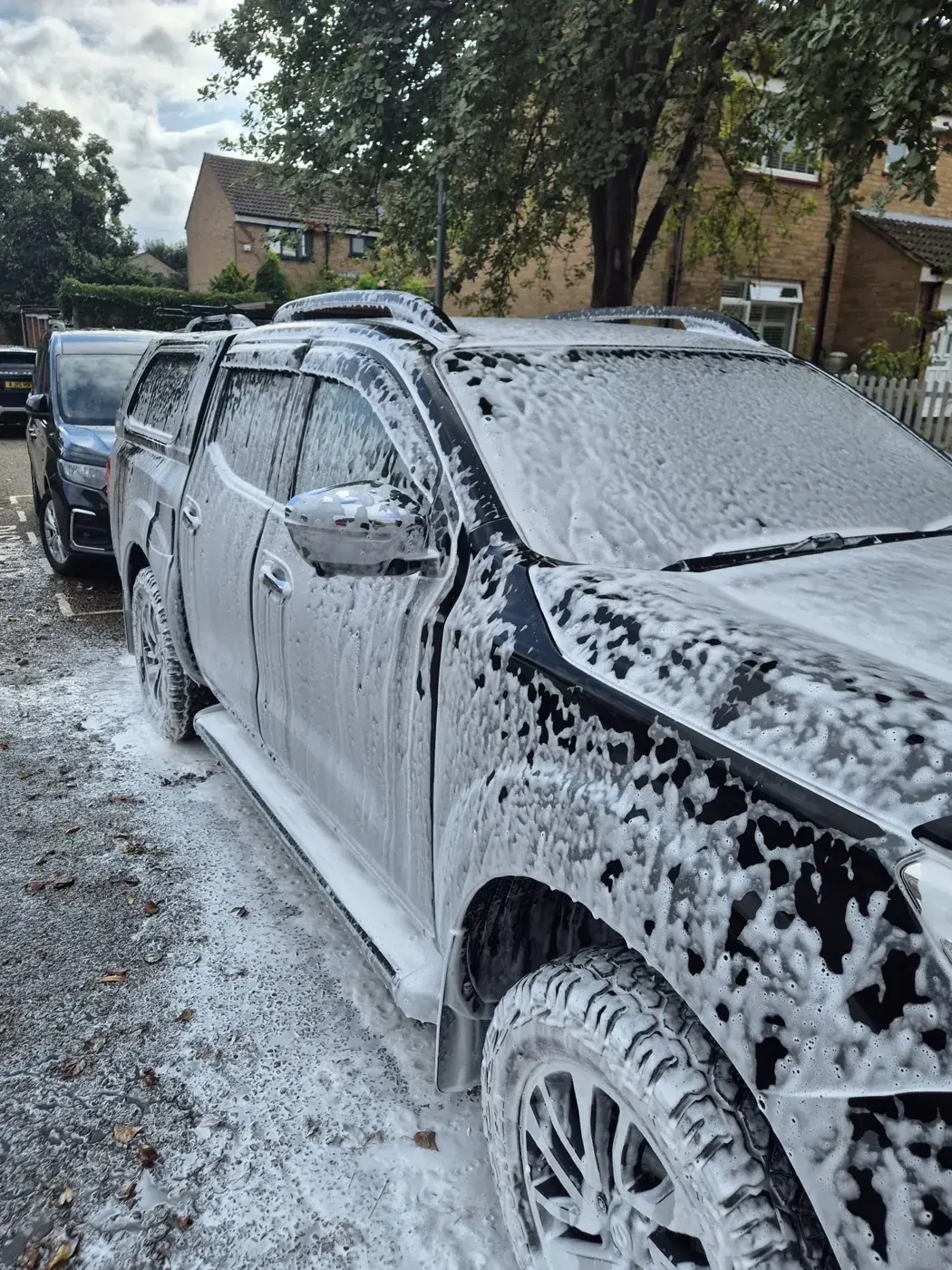 Pickup truck covered in thick snow foam during a mobile wash