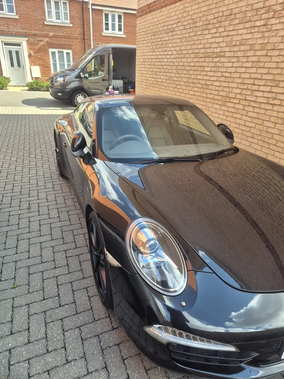 Black Porsche 911 on a block-paved driveway with the VPA van behind it