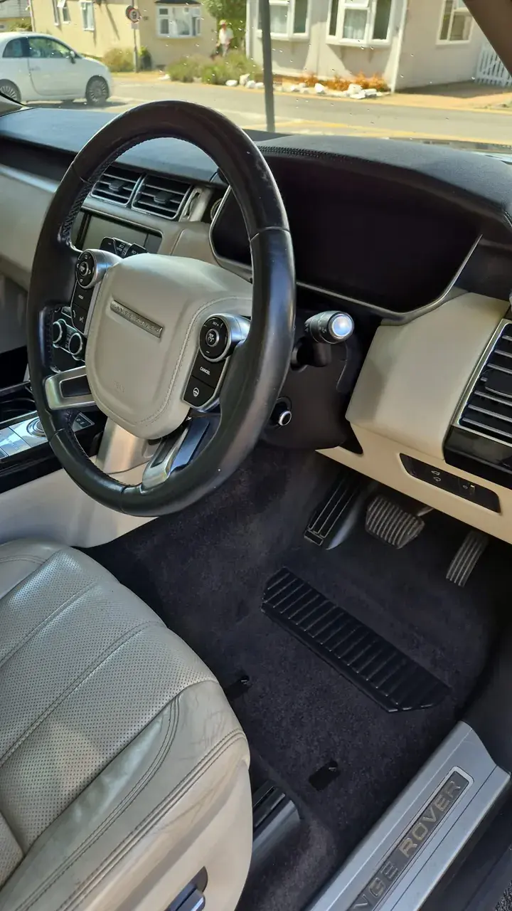 Clean Range Rover steering wheel, cream leather and carpet
